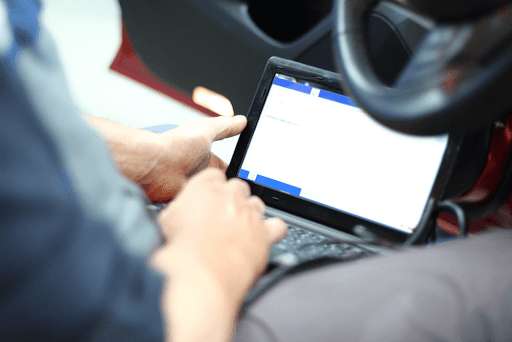 Person using a diagnostic tablet while sitting in a car to check automotive systems.