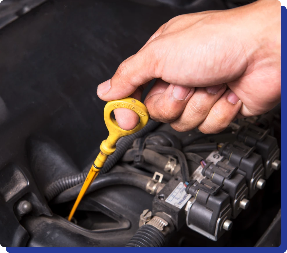 Engine Oil Changes in Kodiak, AK with Midtown Auto Repair Services. Hand pulling out a yellow dipstick from a car engine to check oil level.