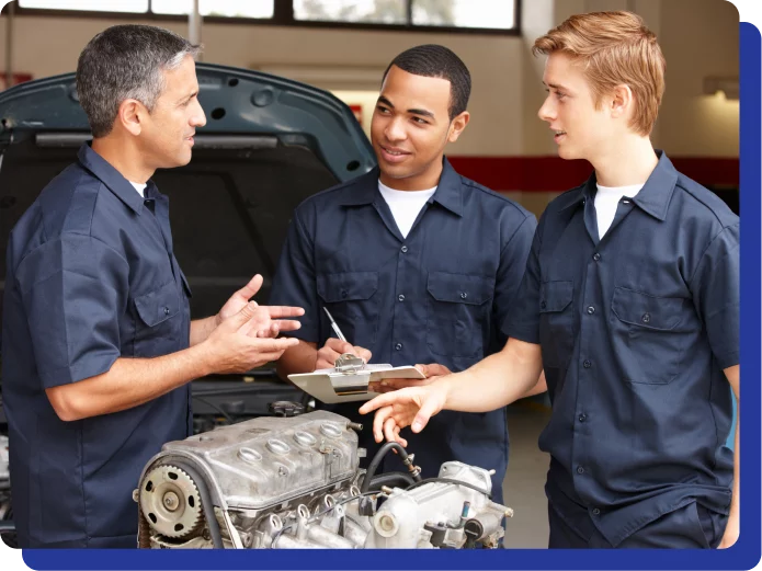 Careers in Kodiak, AK at Midtown Auto Repair Services. Three mechanics discussing work near a car engine, one holding a clipboard.