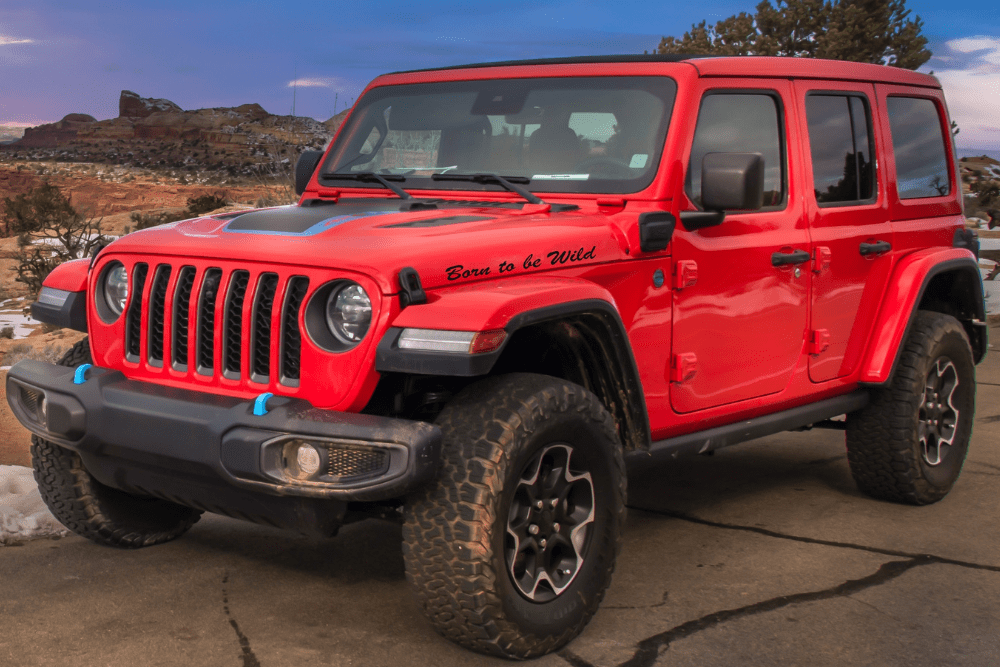 jeep transmission & engine repair, auto repair in Kodiak, AK at Midtown Auto Repair Services. Red Jeep Wrangler parked on a rugged trail with a scenic landscape in the background.
